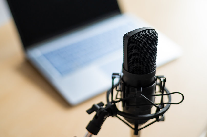 Close-up of a professional microphone on the background of a laptop. Radio broadcaster's desktop